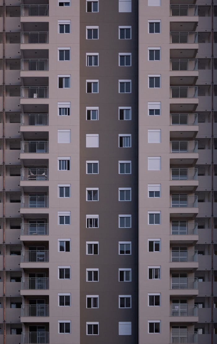 Facade of multistory symmetrical house with balconies and windows in city street in daylight with modern architecture in downtown outside